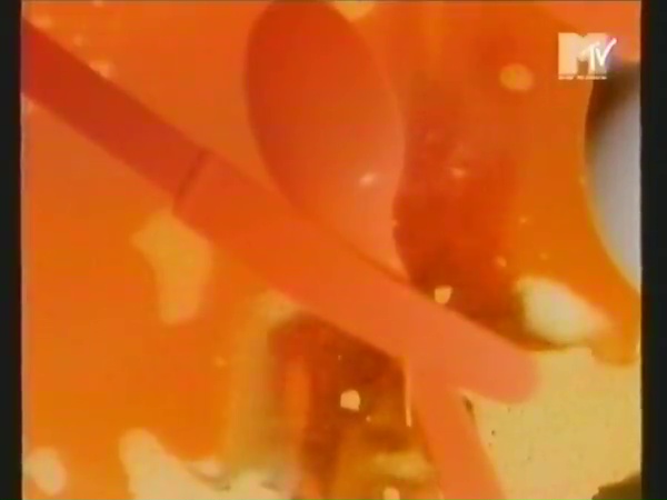 Kuvakaappaus VHS-nauhalta: aterimia tiskivedessä. Kaikki oranssinpunaista; vain oikealla laidalla kanamunanpuolikkaan muotoinen valkea alue. Oikeassa yläkulmassa MTV:n (Music Television) logo.
