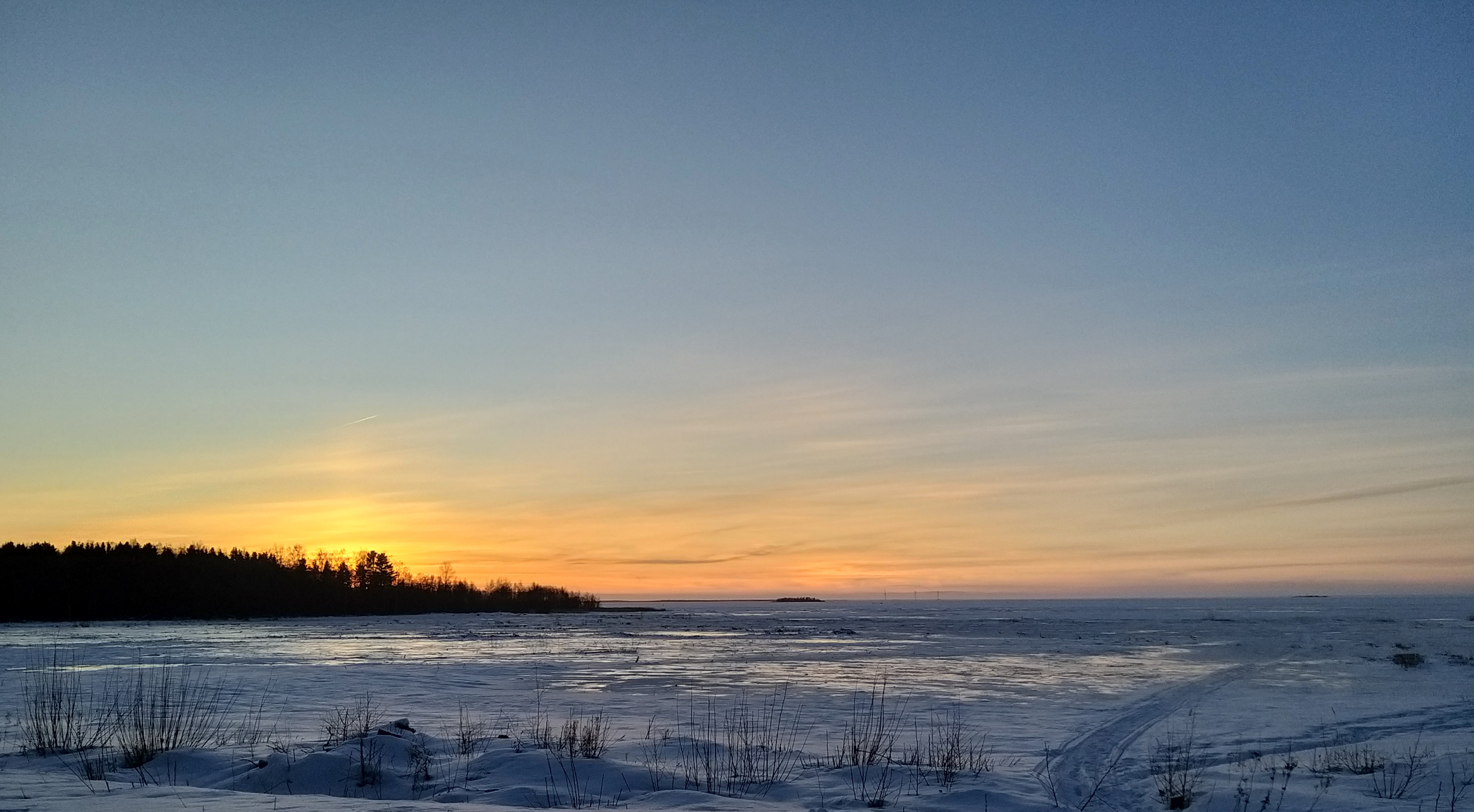 Talvinen auringonlasku meren rannalla.