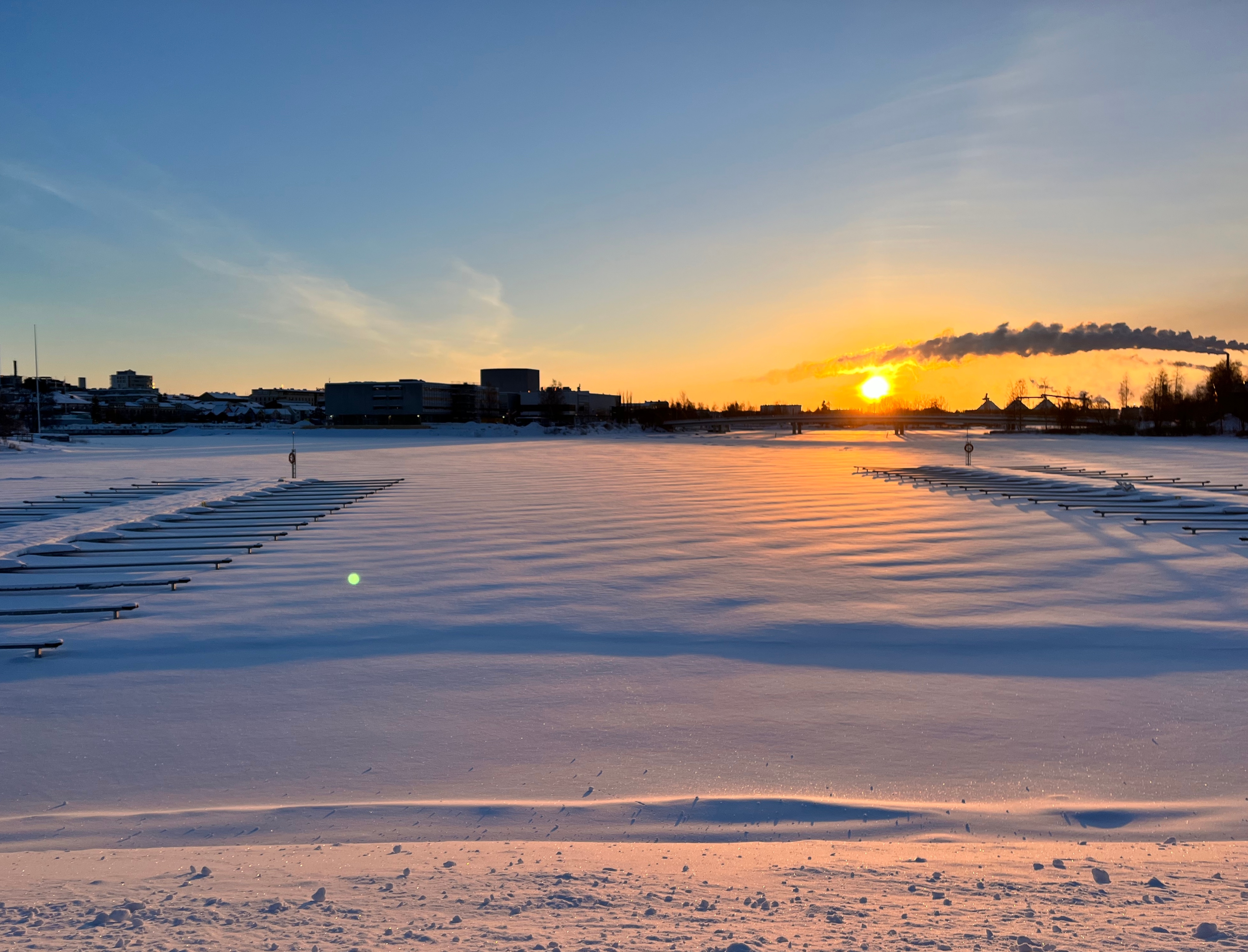 Raatin venesatama talvella, laskevan auringon leijuessa juuri ja juuri Pikisaaren sillan yläpuolella.